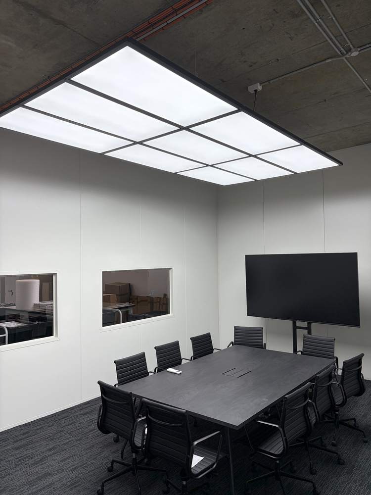 A meeting room with a large backlit ceiling panel and data points run in
