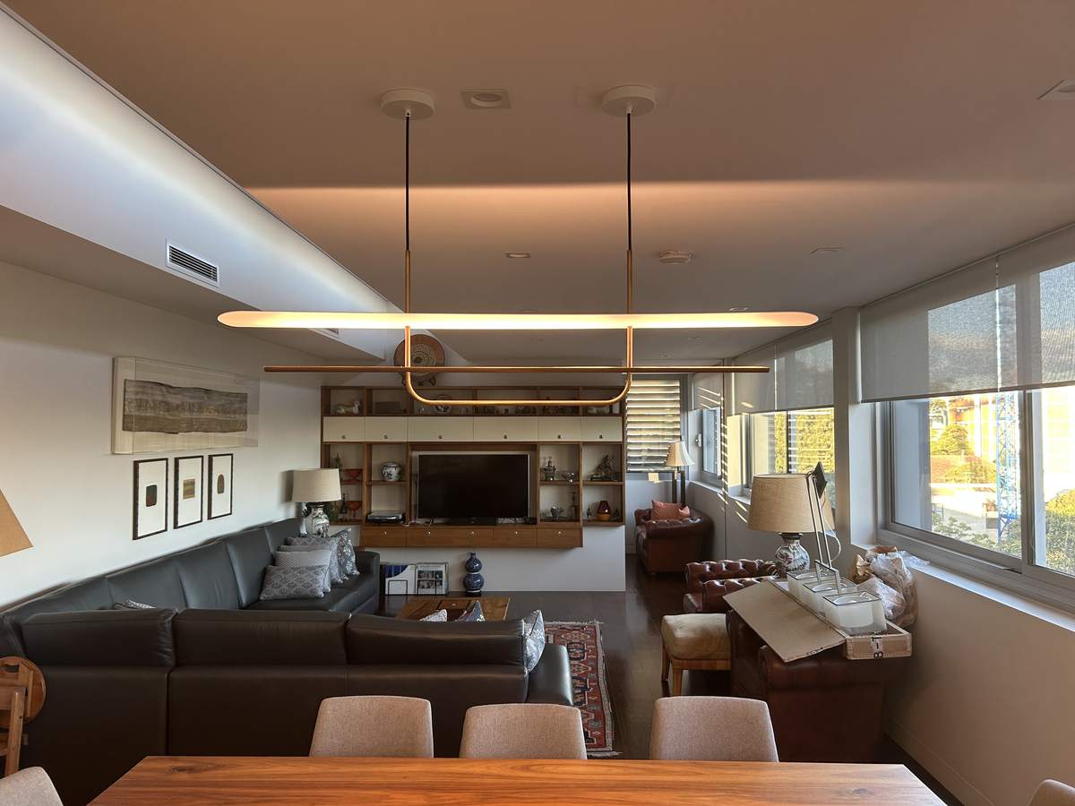 A living and dining room lit by a long linear pendant over the table